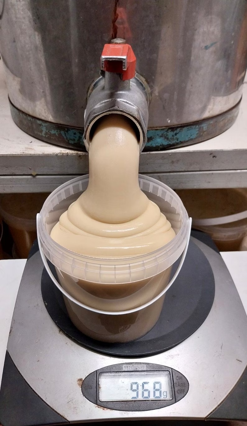 Miel cremada saliendo del madurador a un envase sobre la báscula